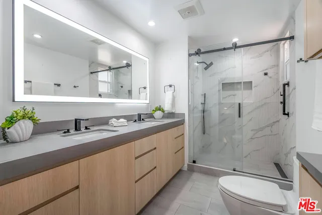 a bathroom with a double vanity sink toilet and shower