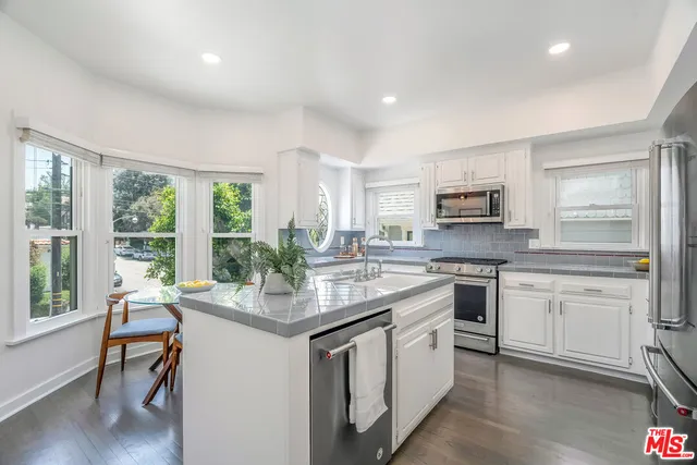 a kitchen with white cabinets and appliances