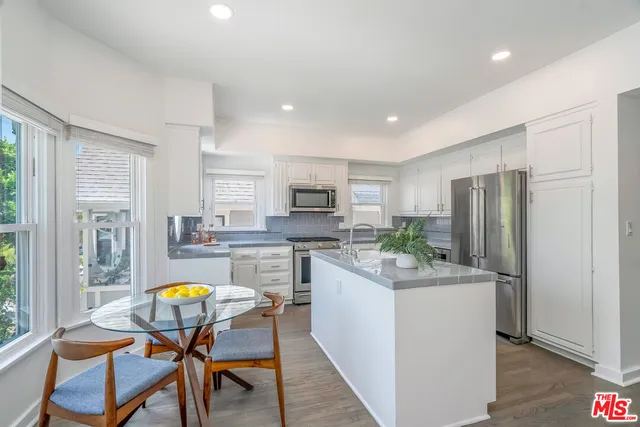 a kitchen with stainless steel appliances kitchen island granite countertop a sink a stove and refrigerator