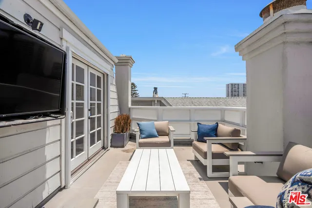 a view of roof deck with furniture and tv