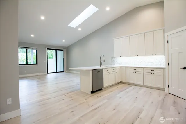 a large white kitchen with a white countertops a sink and a window