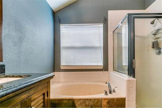 a bathroom with a granite countertop bathtub and next to a window