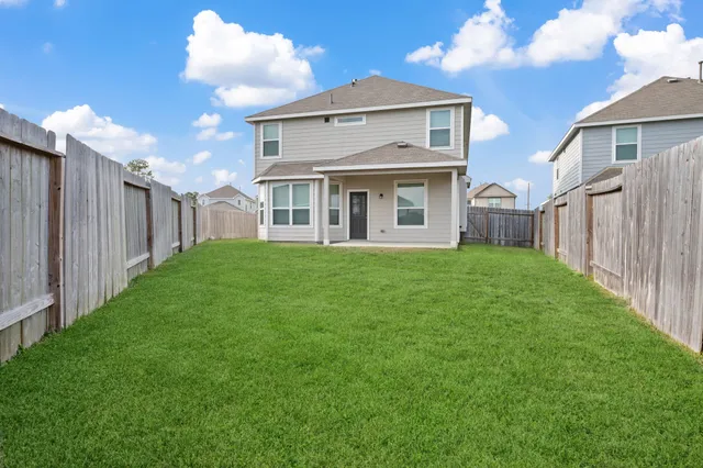 a view of a house with a yard and a large tree