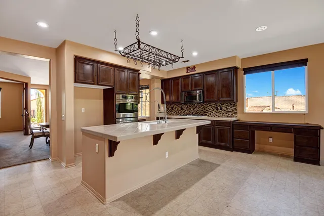 a kitchen with stainless steel appliances kitchen island granite countertop a stove refrigerator and cabinets