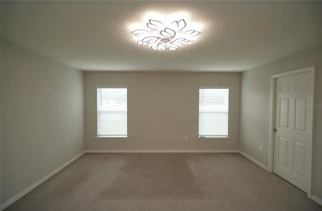 an empty room with a window and a chandelier fan