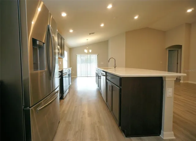 a kitchen with stainless steel appliances kitchen island a refrigerator sink and cabinets