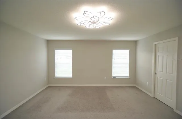 an empty room with a window and a chandelier fan
