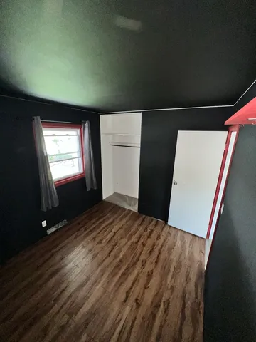 a view of empty room with window and wooden floor