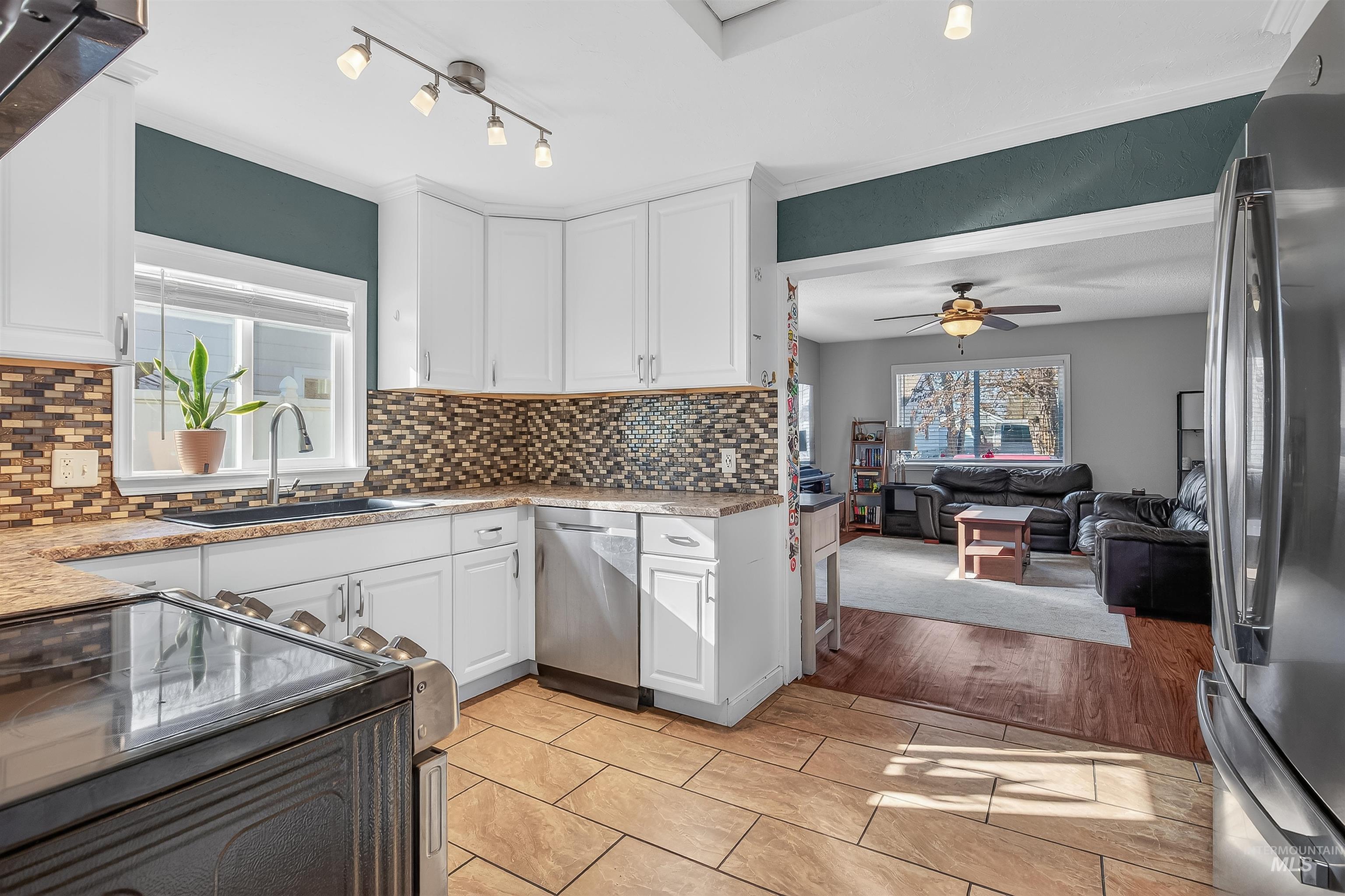 807 3rd Street Clarkston, WA 99403 - Photo 11 of 33 Kitchen featuring stainless steel appliances, white cabinetry, light stone counters, tasteful backsplash, and a ceiling fan