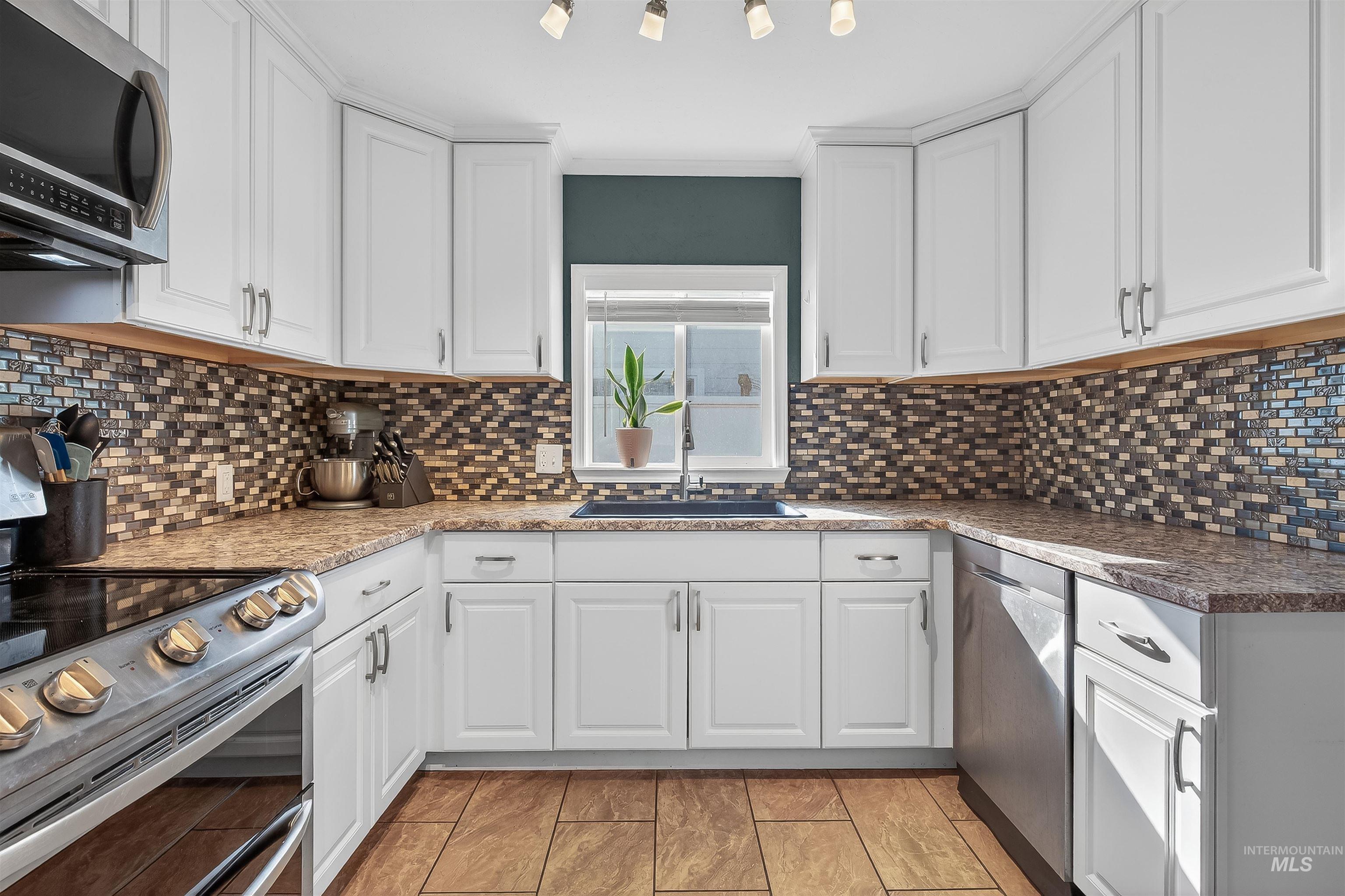 807 3rd Street Clarkston, WA 99403 - Photo 12 of 33 Kitchen with stainless steel appliances, white cabinets, crown molding, tasteful backsplash, and dark stone countertops