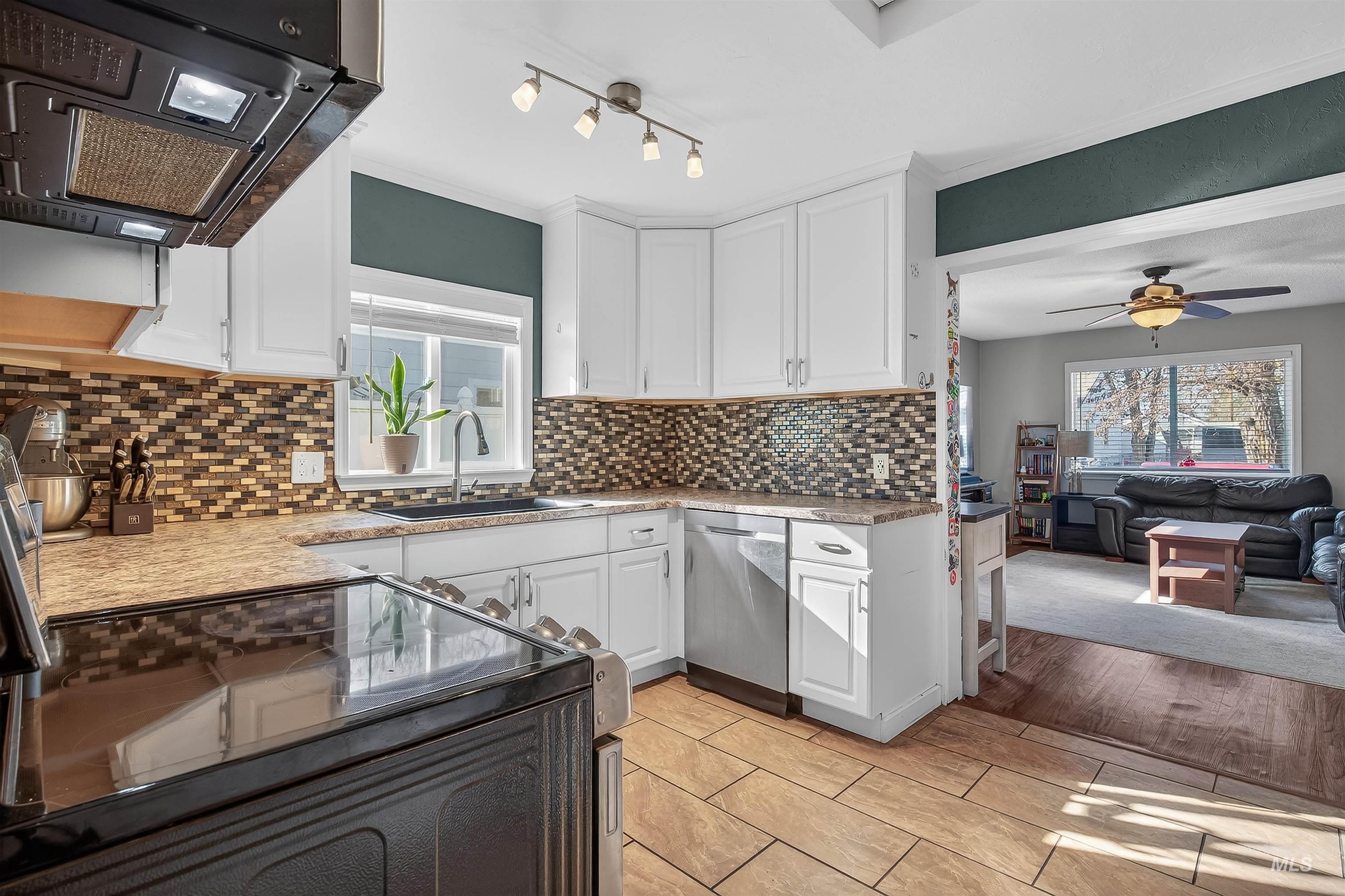807 3rd Street Clarkston, WA 99403 - Photo 13 of 33 Kitchen featuring ventilation hood, electric range, white cabinetry, ceiling fan, and ornamental molding