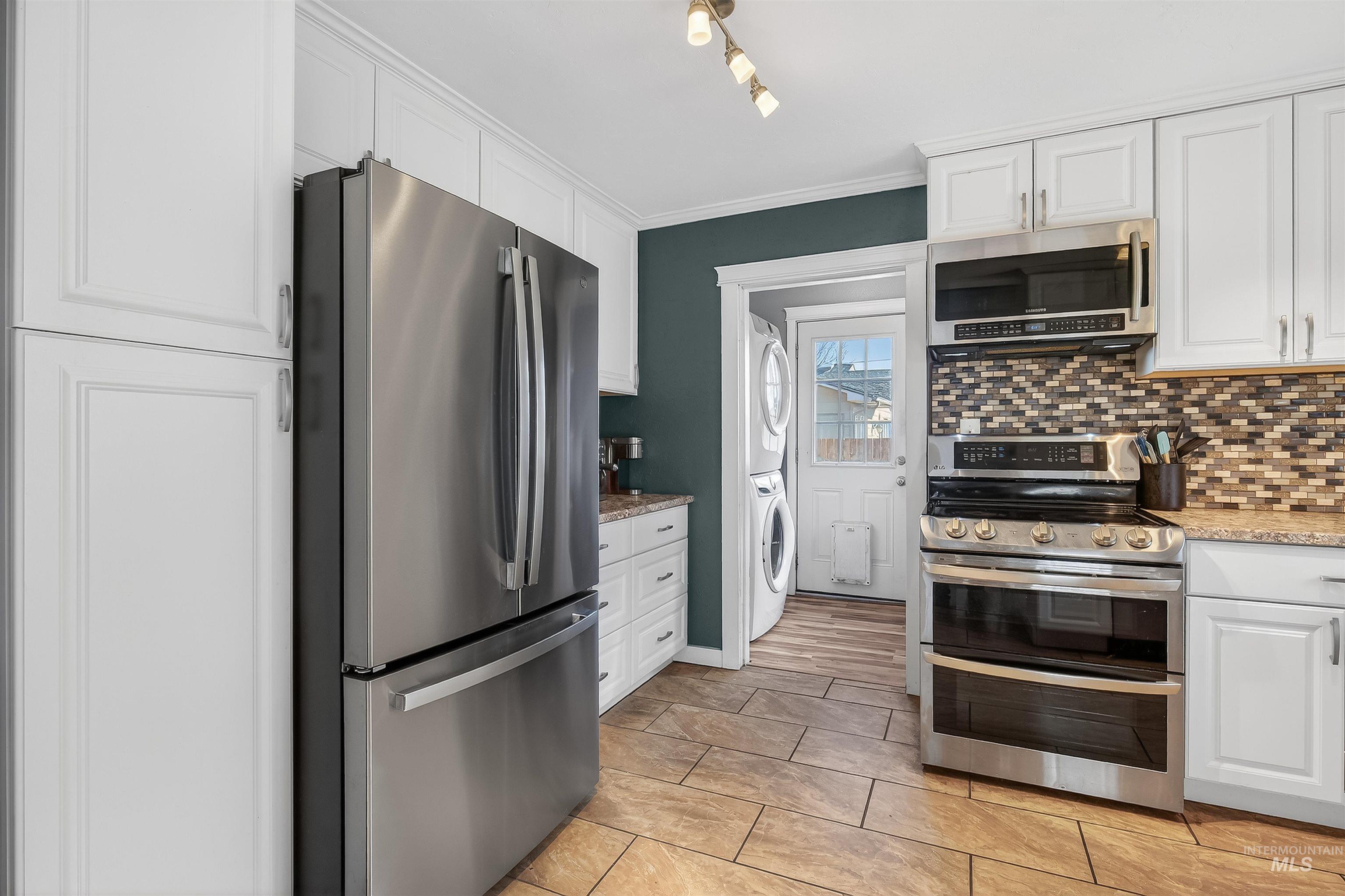 807 3rd Street Clarkston, WA 99403 - Photo 14 of 33 Kitchen with stainless steel appliances, white cabinetry, crown molding, stacked washer / dryer, and light stone countertops