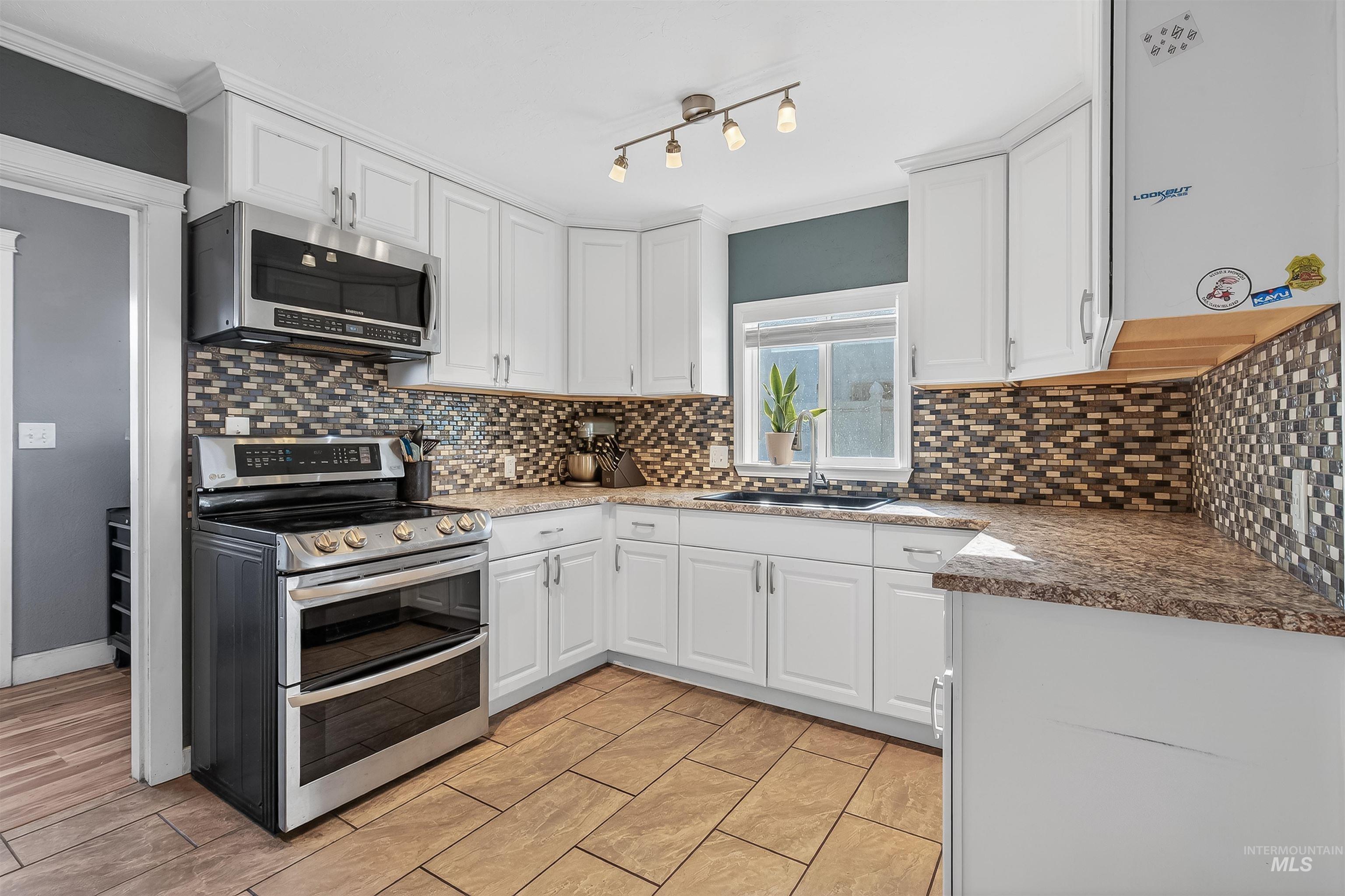 807 3rd Street Clarkston, WA 99403 - Photo 15 of 33 Kitchen with stainless steel appliances, white cabinetry, ornamental molding, and tasteful backsplash