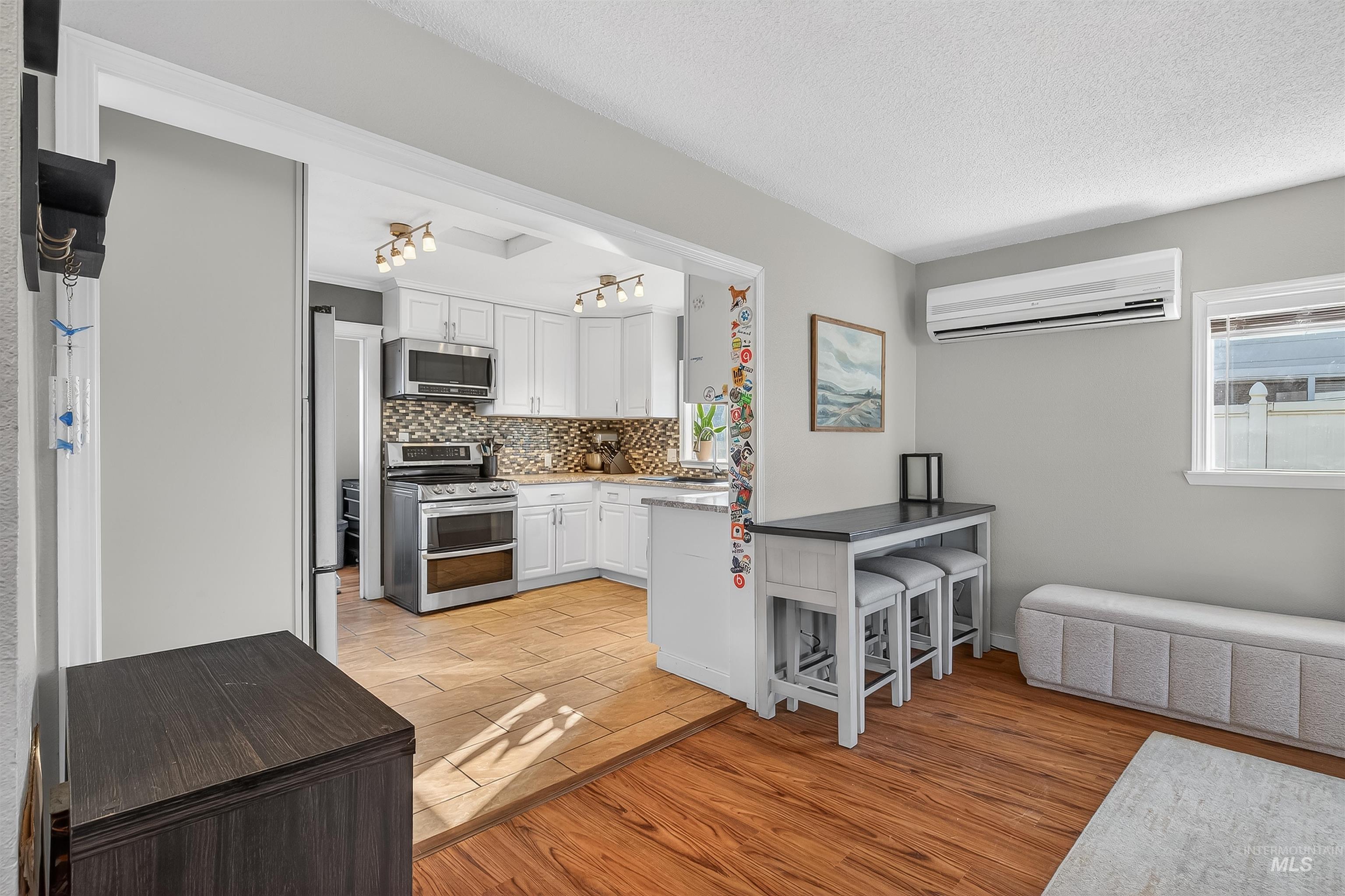 807 3rd Street Clarkston, WA 99403 - Photo 16 of 33 Kitchen with white cabinetry, stainless steel appliances, light wood-style floors, a breakfast bar area, and tasteful backsplash