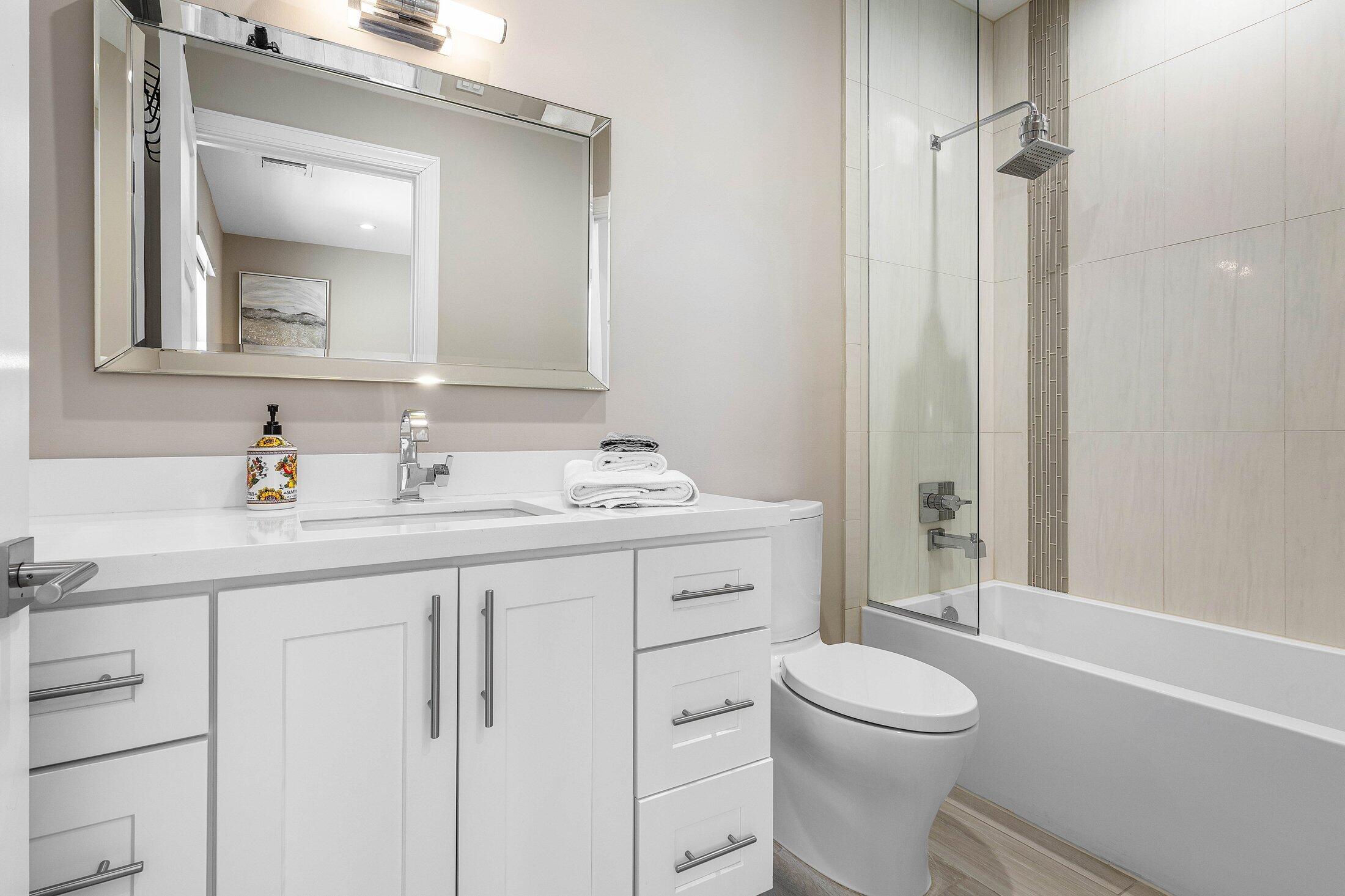 1400 Lake Drive Delray Beach, FL 33444 - Photo 34 of 121 a bathroom with a toilet a sink a mirror a vanity and window