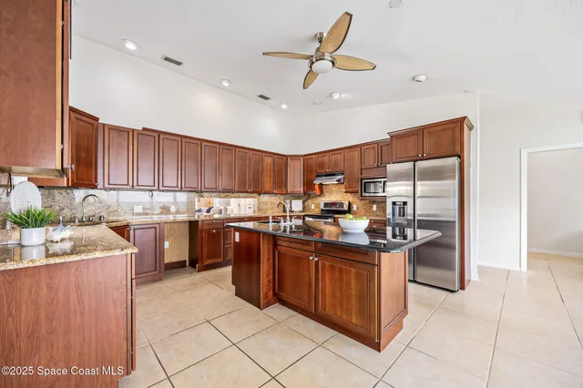 a kitchen with kitchen island granite countertop a sink counter top space appliances and cabinets