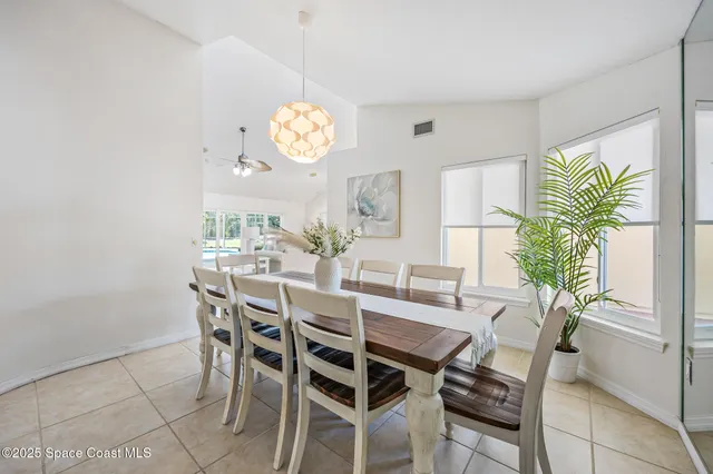 a view of a dining room and kitchen with furniture a chandelier and wooden floor