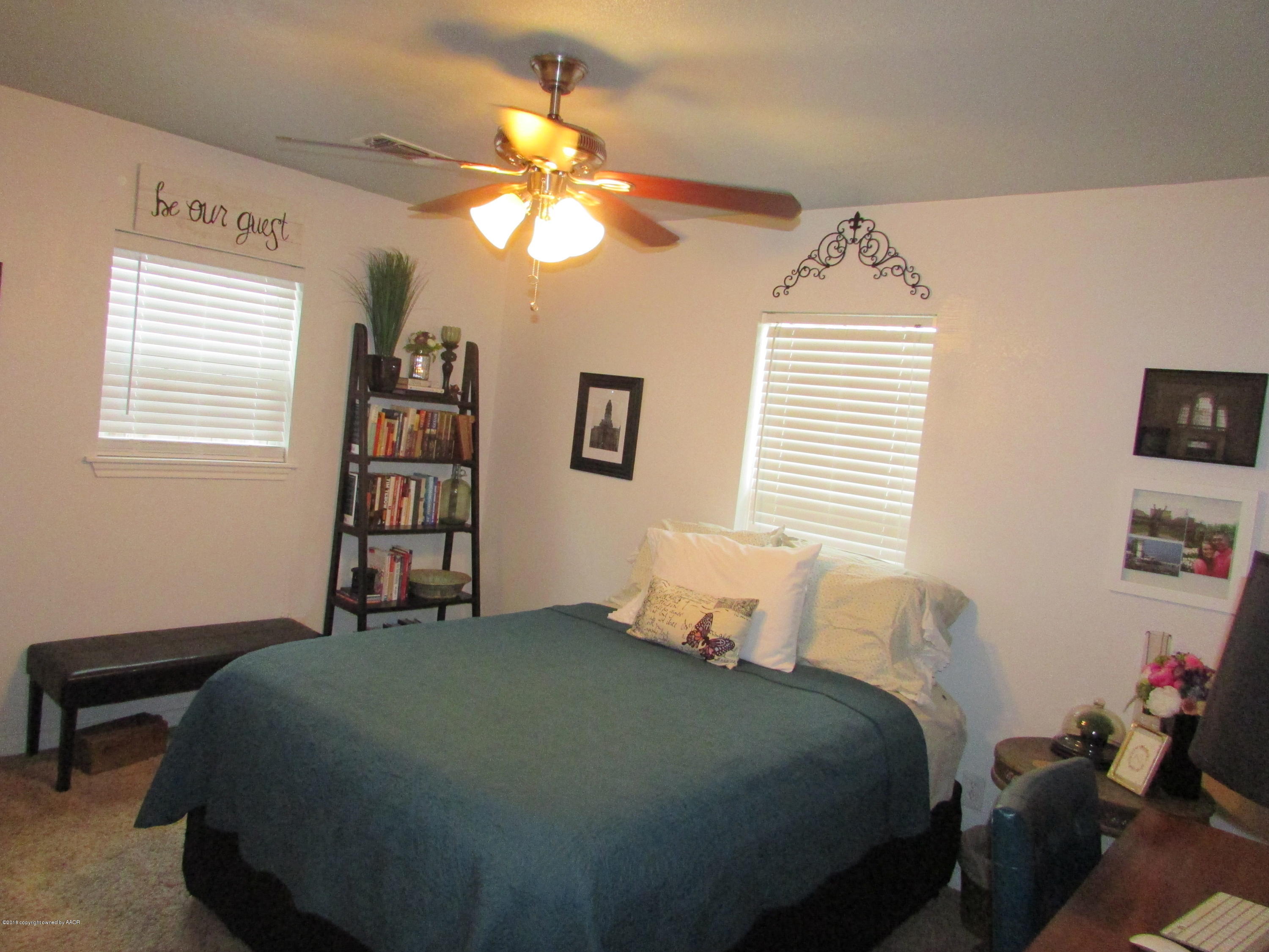 4605 South Travis Street Amarillo, TX 79110 - Photo 11 of 17 a bedroom with a bed a window and a chandelier