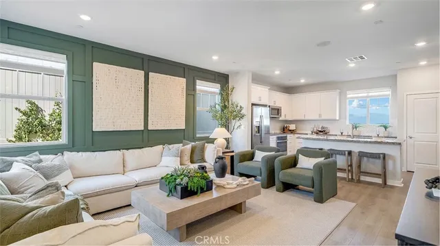 a living room with furniture kitchen view and a large window