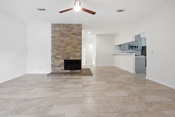 a view of kitchen and empty room with fireplace
