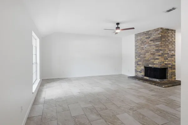 an empty room with windows and fireplace