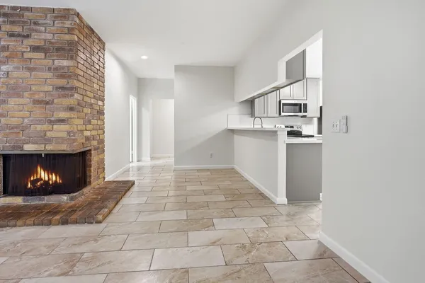 a view of empty room with kitchen and fireplace