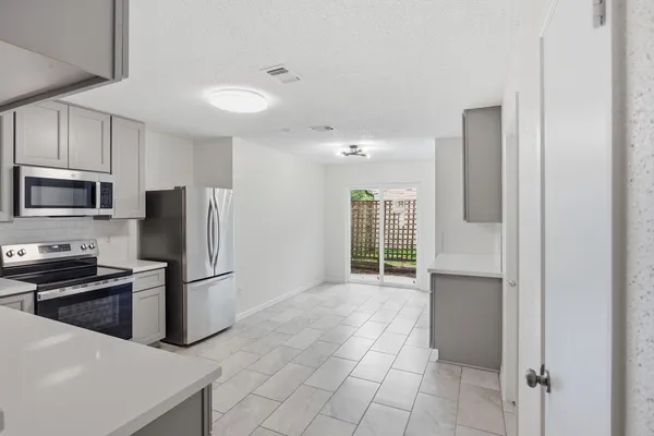 a kitchen with granite countertop a refrigerator and a stove top oven