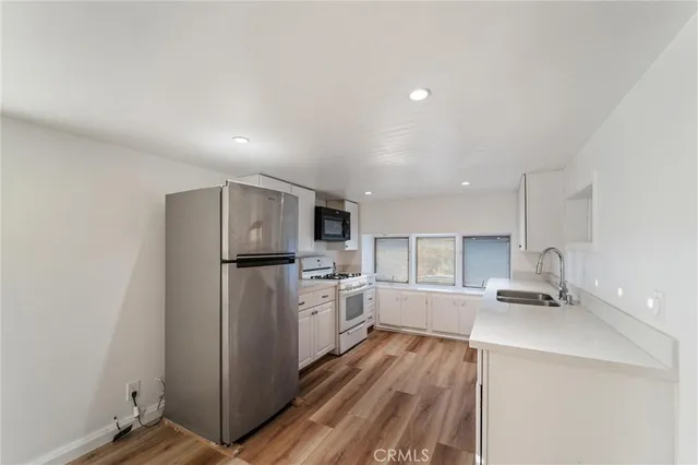 a kitchen with a refrigerator a stove top oven and white cabinets