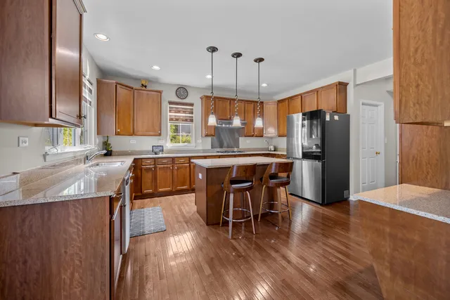 a kitchen with stainless steel appliances granite countertop a table chairs refrigerator and sink