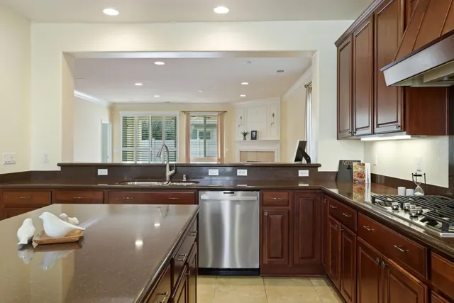 a kitchen with stainless steel appliances granite countertop a refrigerator a sink a stove and a refrigerator