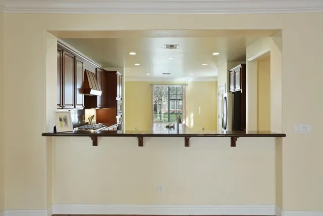 a room with stainless steel appliances granite countertop a refrigerator a sink dishwasher a stove and a dining table with wooden floor