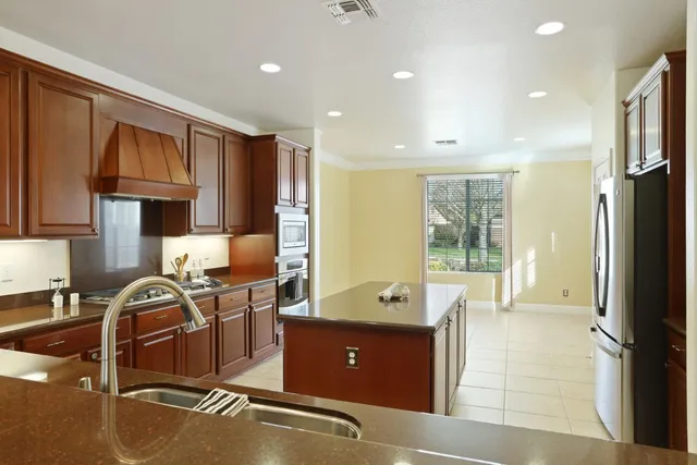 a room with stainless steel appliances granite countertop a sink refrigerator and cabinets