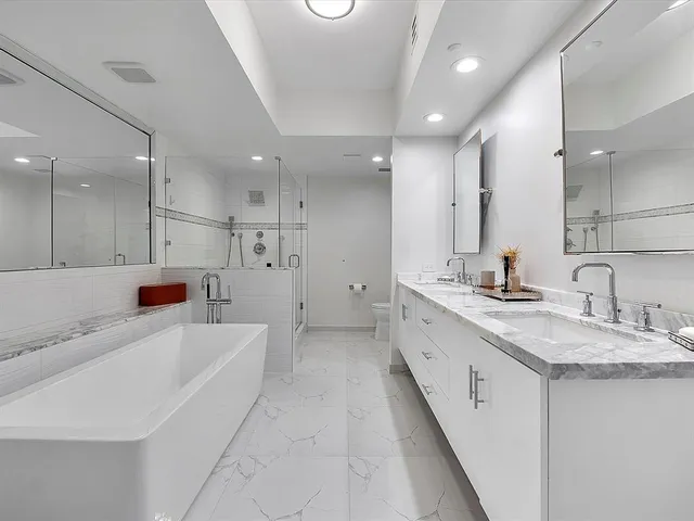 a large white bathroom with a granite countertop sink a bathtub and a shower