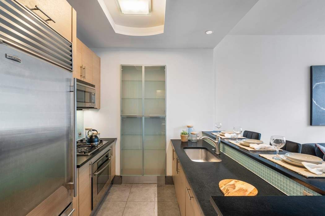 325 5th Avenue, Unit 18F Manhattan, NY 10016 - Photo 5 of 13 a kitchen with stainless steel appliances granite countertop a sink and a stove