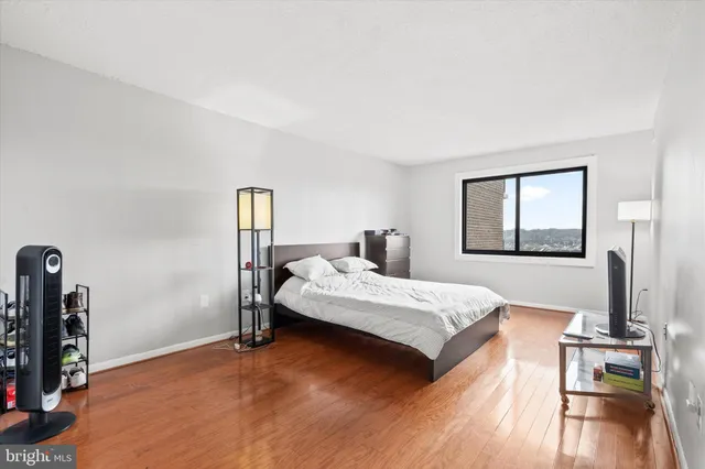 a bedroom with a bed table and a flat screen tv