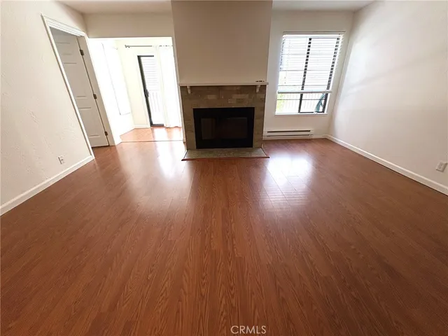 an empty room with wooden floor fireplace and windows