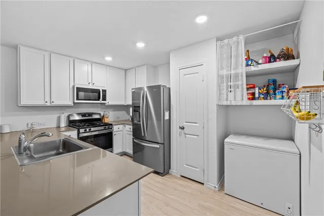 a kitchen with refrigerator a microwave a sink and cabinets