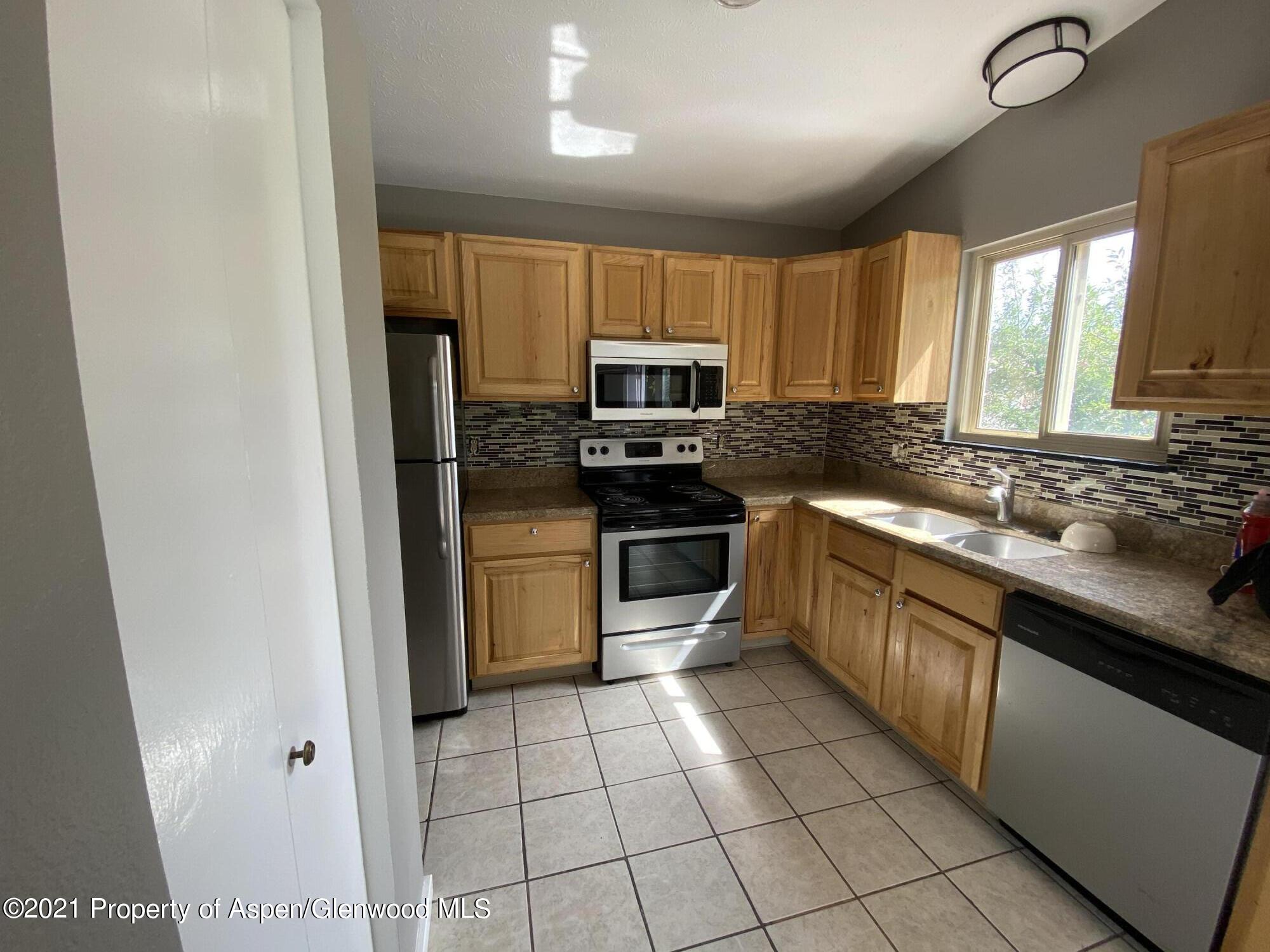 317 Clarkson Avenue Rifle, CO 81650 - Photo 5 of 17 a kitchen with stainless steel appliances granite countertop a stove a sink and a refrigerator