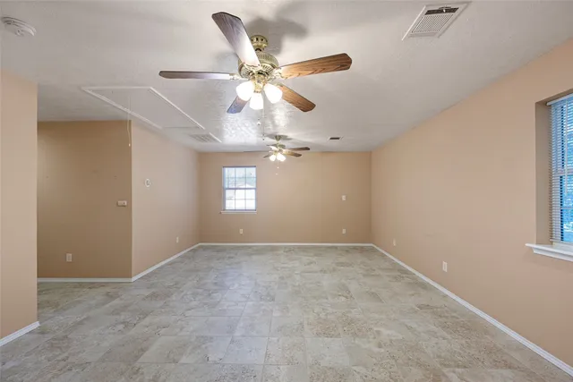 an empty room with windows and fan