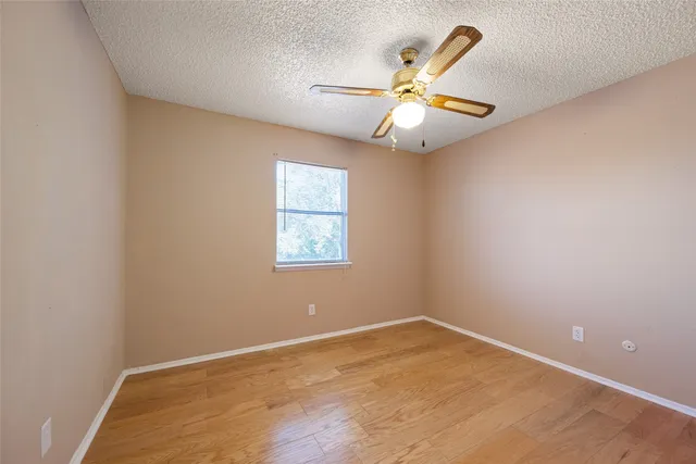 an empty room with a window and ceiling fan