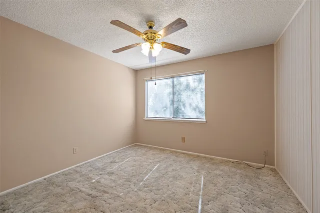 an empty room with a window and a ceiling fan