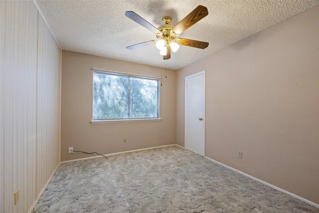 an empty room with windows and ceiling fan