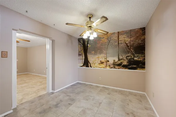 an empty room with wooden floor and fan