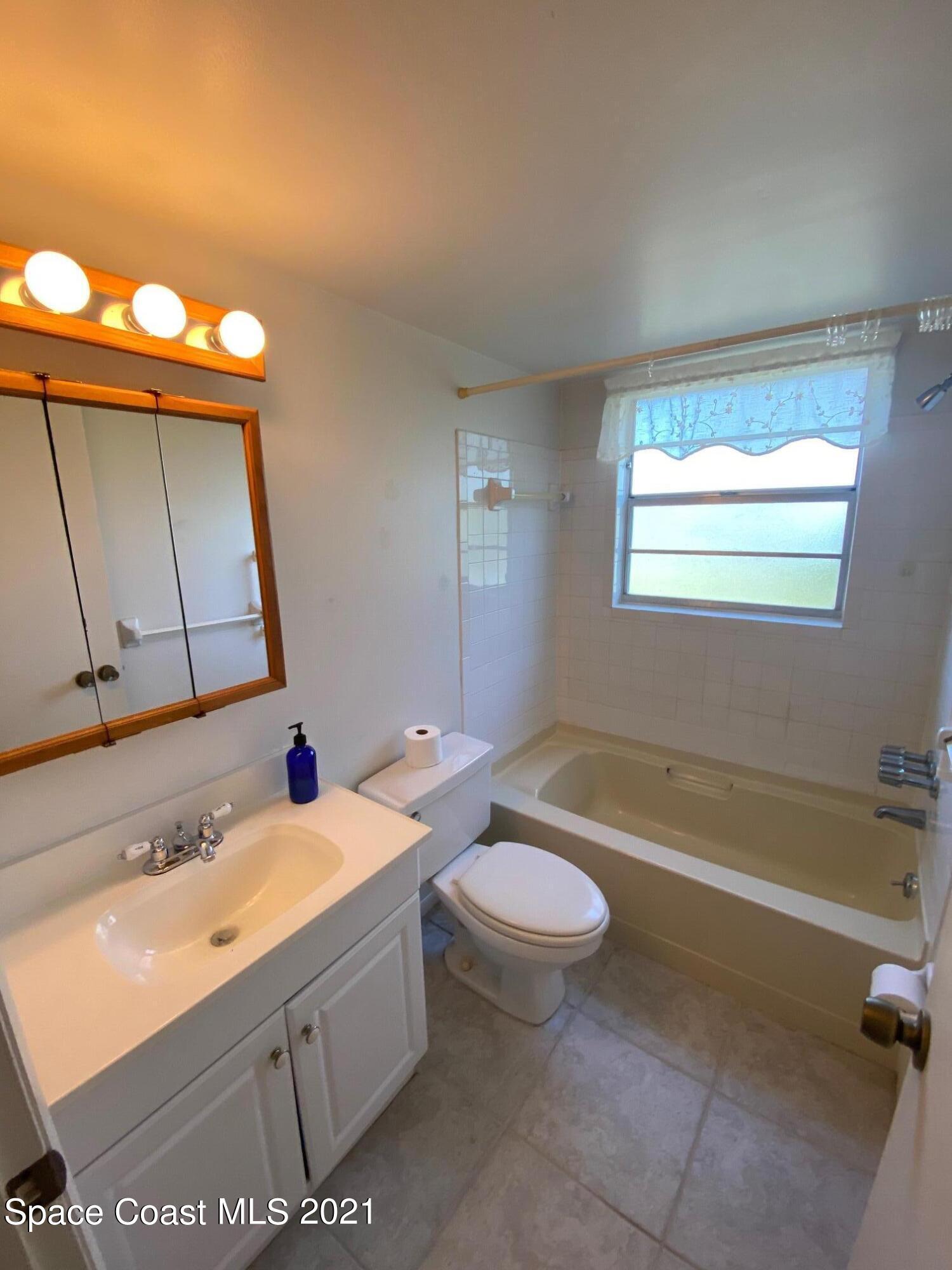 3135 Shady Dell Lane, Unit 112 Melbourne, FL 32935 - Photo 15 of 22 a bathroom with a sink a toilet a mirror and bathtub
