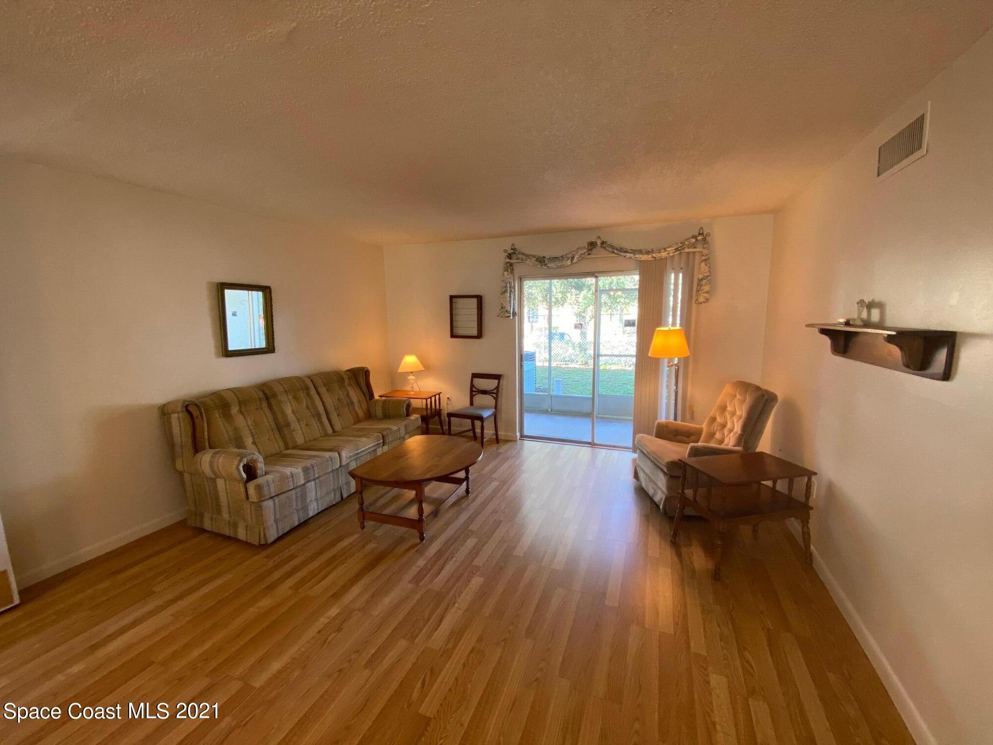 3135 Shady Dell Lane, Unit 112 Melbourne, FL 32935 - Photo 3 of 22 a living room with furniture and a wooden floor