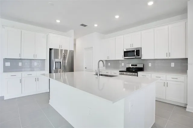 a kitchen with white cabinets and stainless steel appliances