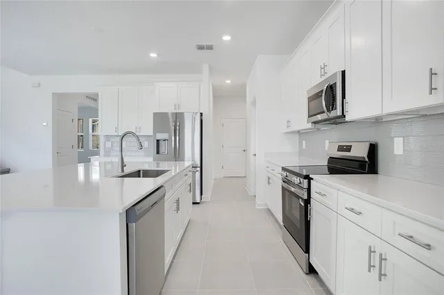 a kitchen with stainless steel appliances granite countertop a sink a stove and a refrigerator