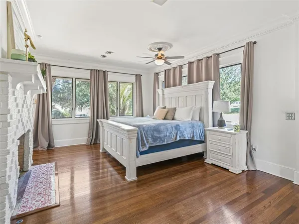 a bedroom with a bed next to a large window with wooden floor