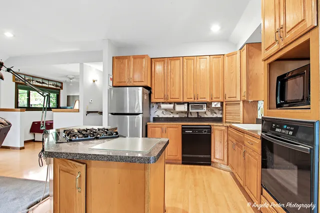 a kitchen with granite countertop stainless steel appliances a stove refrigerator sink and cabinets