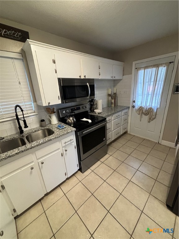 1307 Sherry Lane, Unit B Copperas Cove, TX 76522 - Photo 25 of 48 a kitchen with granite countertop a sink a stove top oven and cabinetry